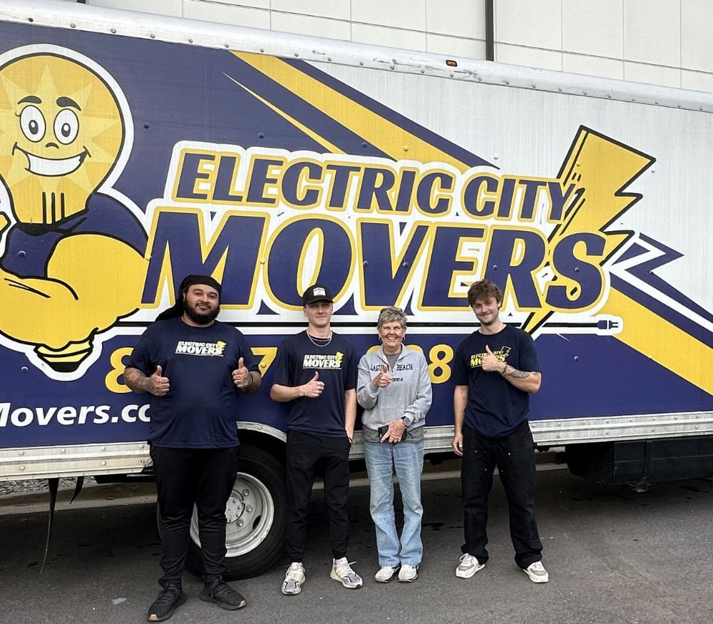 Three Electric City Movers LLC crew members and a satisfied customer giving thumbs up in front of a branded moving truck in Anderson, SC