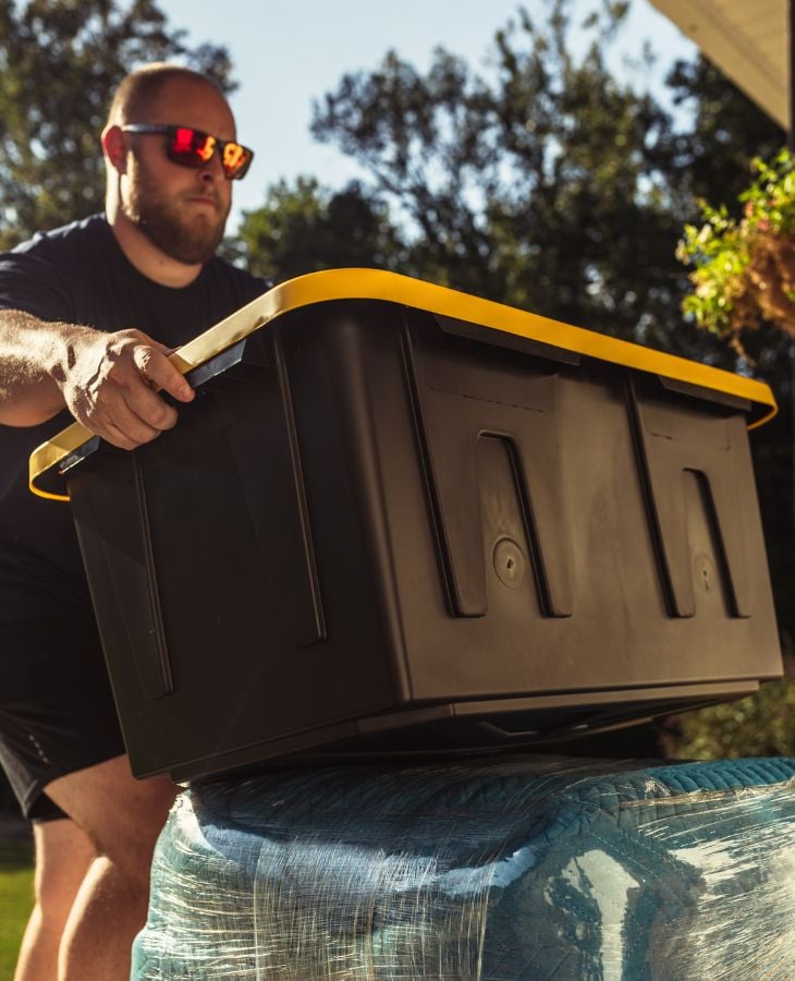 Electric City Movers LLC crew member carefully handling a large black and yellow storage tote on top of wrapped belongings during a residential move in Anderson, SC