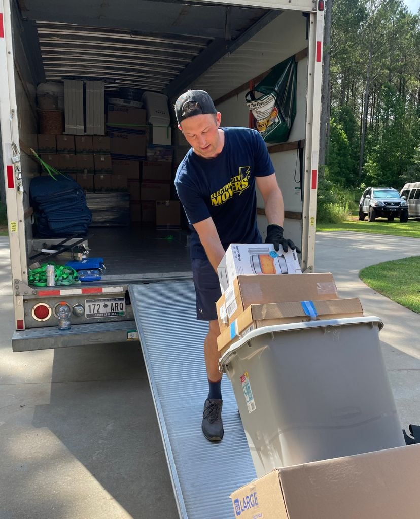 Electric City Movers LLC crew member unloading boxes and belongings from a moving truck using a loading ramp during a local move in Anderson, SC